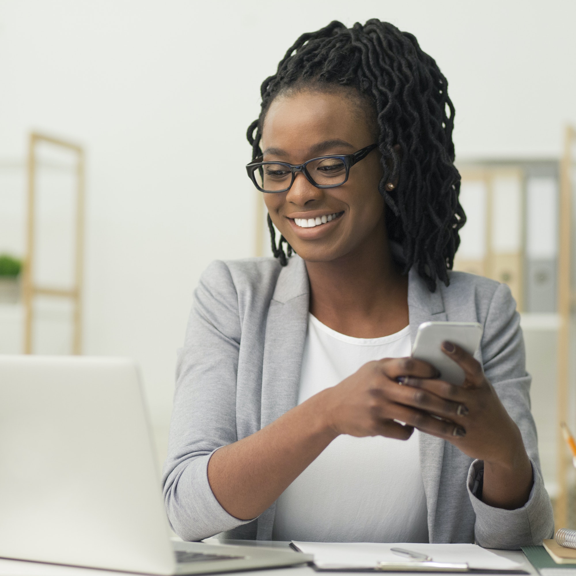Afro Businesswoman Texting Via Smartphone Sitting In Modern Office